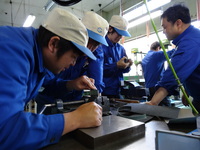 サイコロ製作のヤスリ掛け。上手くいかず、新人も教育者も必死。